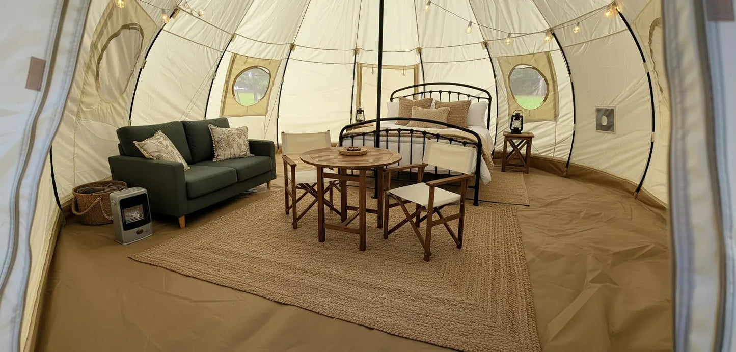 Interior of a tent with living room furniture including a sofa, table, and chairs.