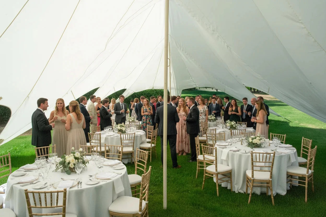 Wedding reception under a large white tent with guests and tables.