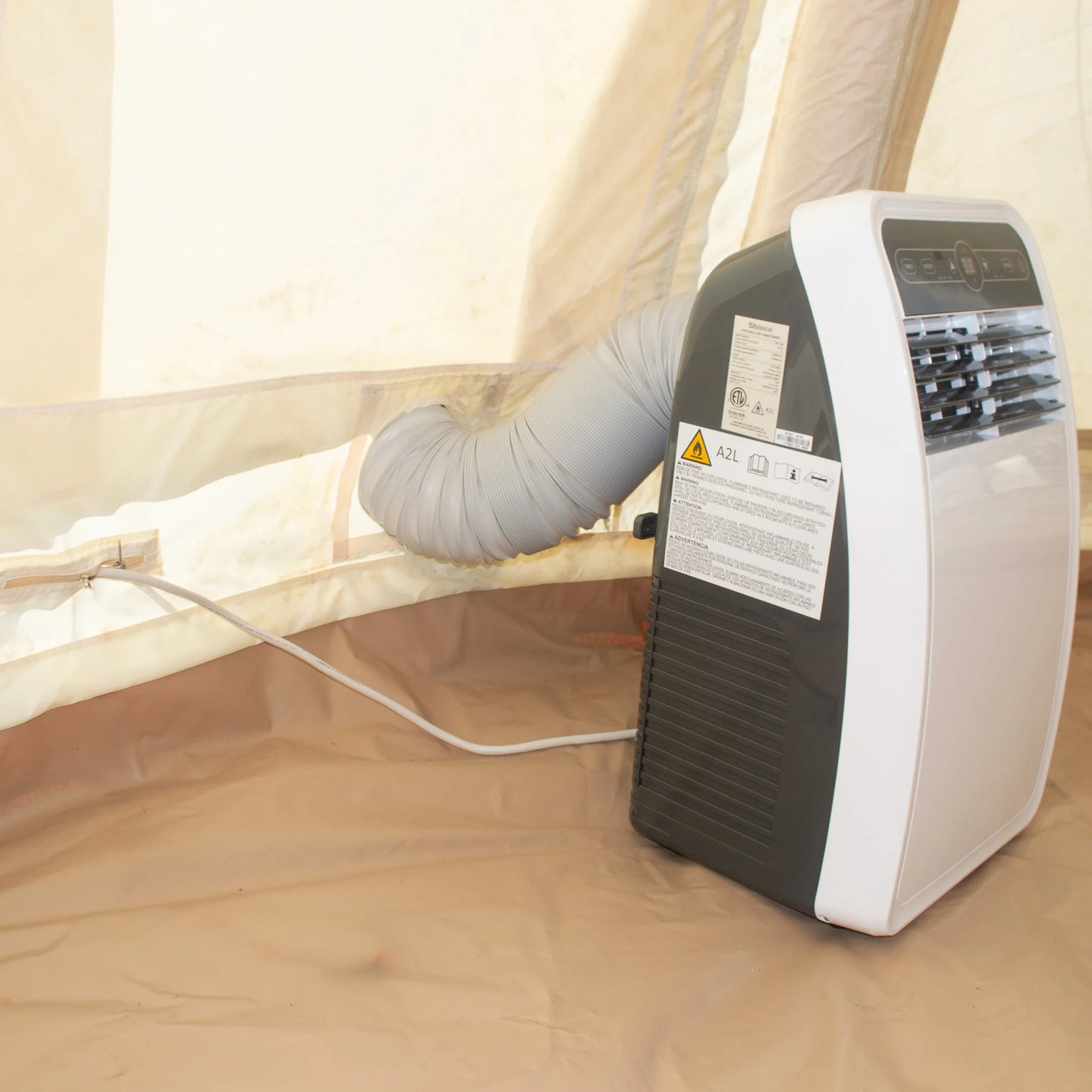 Portable air conditioner with duct connected to a tent on a wooden floor.