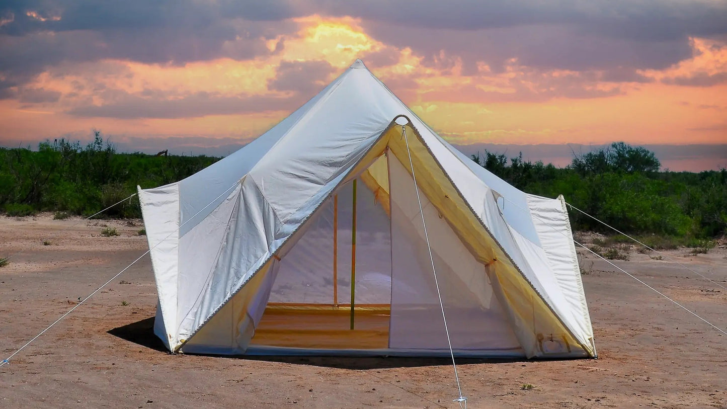 White tent in a desert landscape with a colorful sunset sky