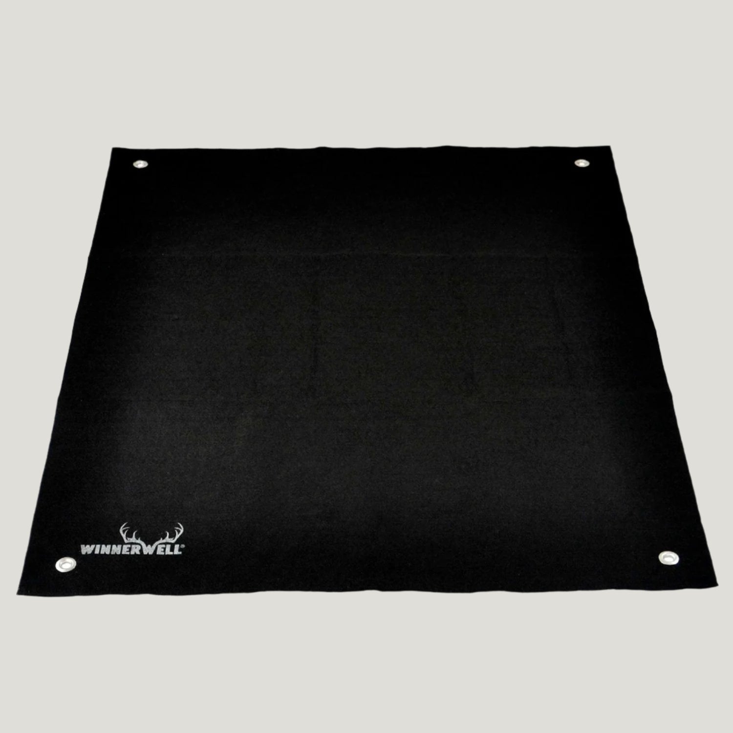 A black, rectangular Winnerwell mat made of fireproof carbon fiber and aluminum foil, designed for use with wood-burning stoves to protect tent floors.