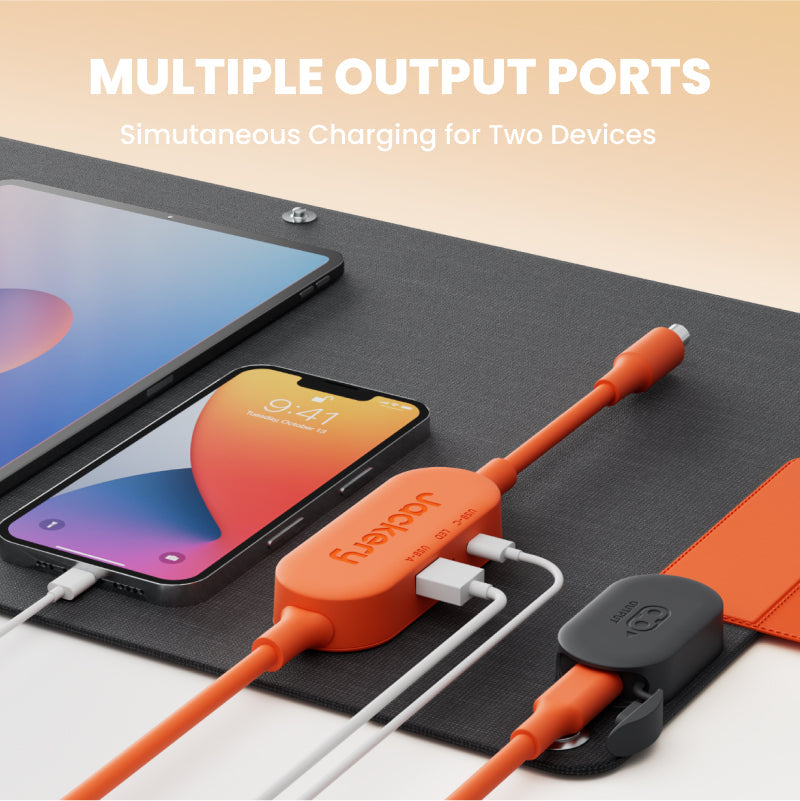 Orange charging cable with multiple output ports charging two devices on a black surface.
