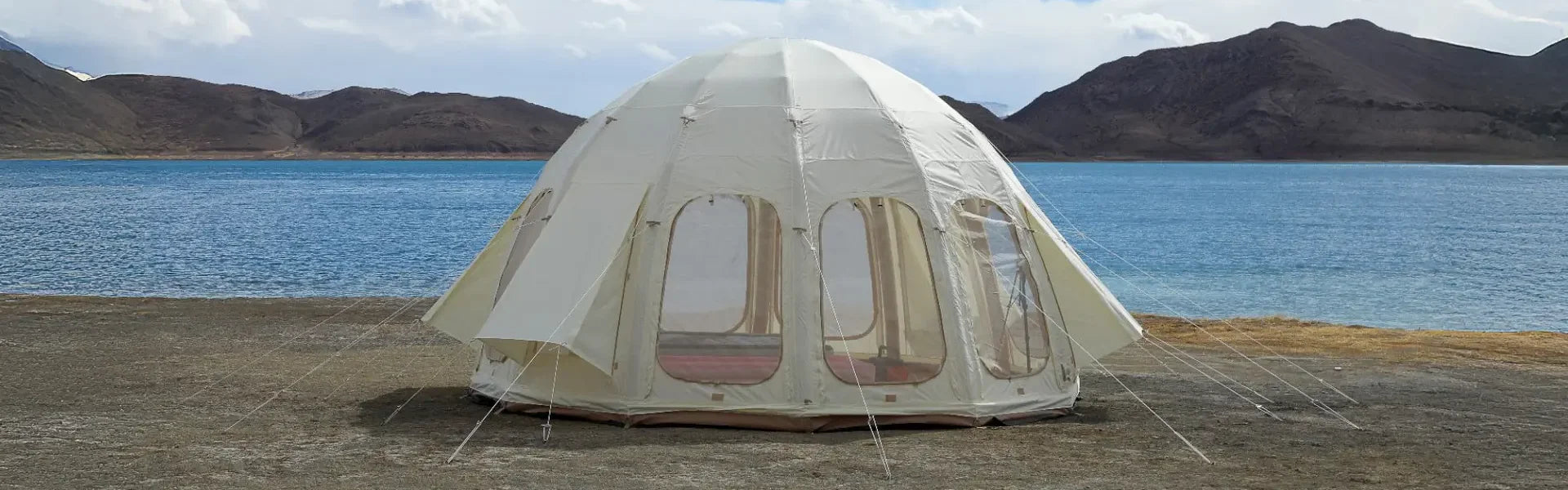 Tent set up near a body of water with mountains in the background