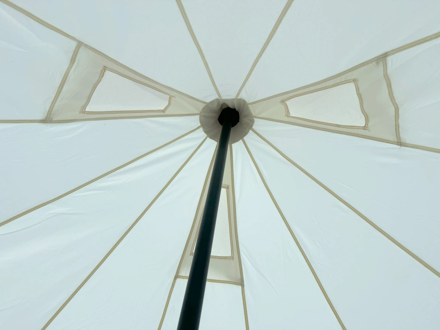 Close-up of a white umbrella with a black rod against a light blue background