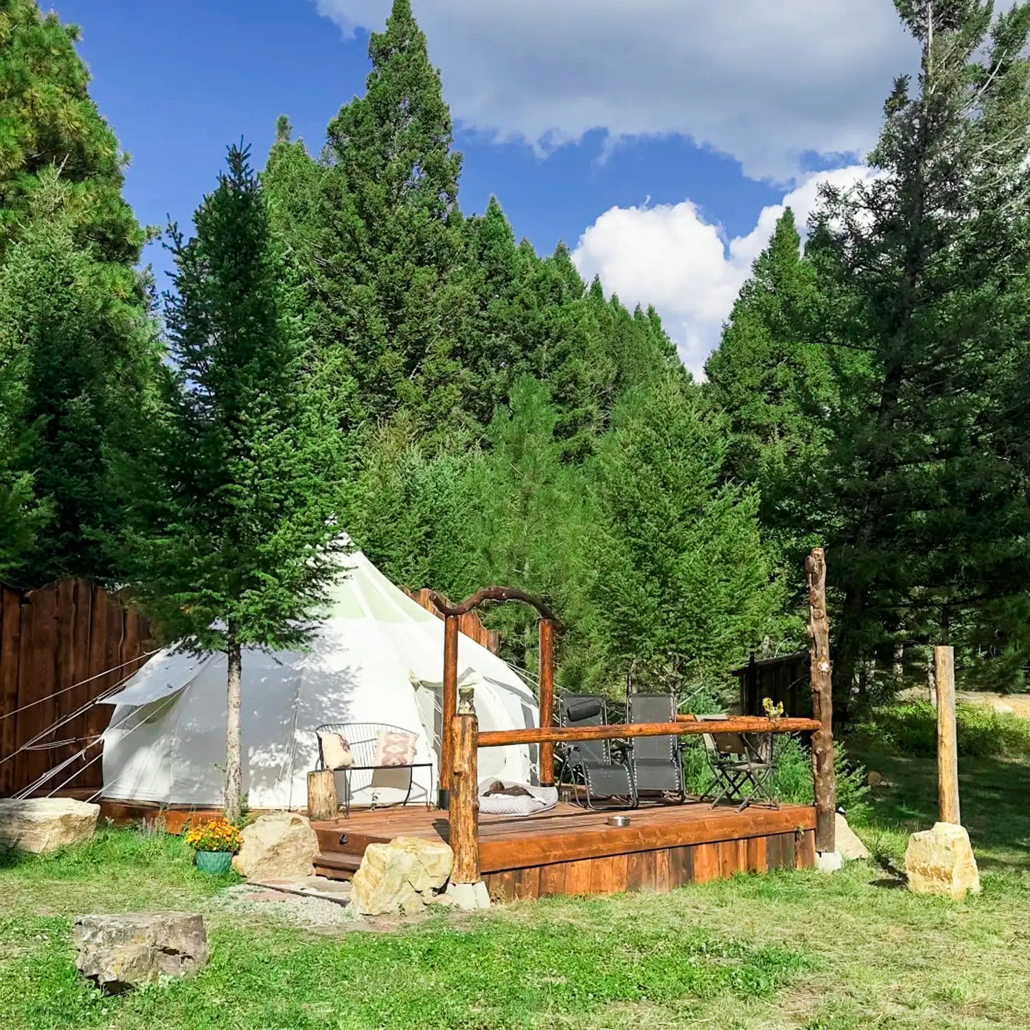 Tent and wooden deck in a forest setting with clear blue sky