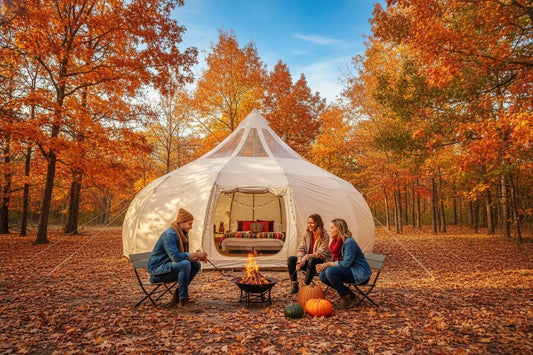 A glamping tent surrounded by bright orange and red fall foliage with warm light glowing from inside