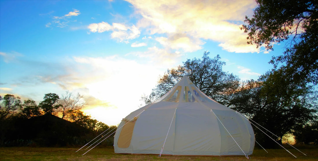 Glamping tent set up in the Texas Hill Country with oak trees and wildflowers in golden evening light