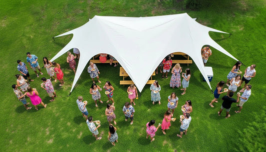 Group of people gathered under a large white tent on a grassy field
