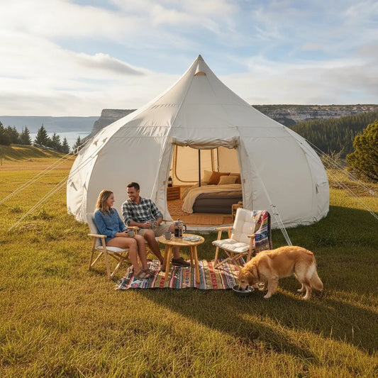 Couple sitting outside a large white tent with a dog on a grassy field.