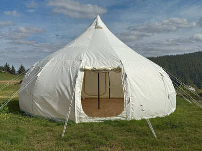 White bell tent in a grassy field with a blue sky and clouds