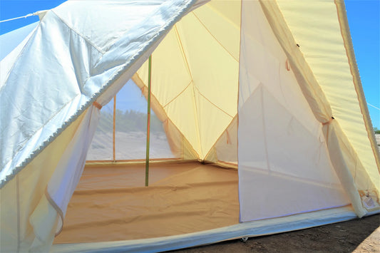 Partial view of a tent with a wooden floor and white walls against a blue sky.