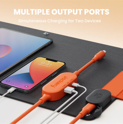Orange charging cable with multiple output ports charging two devices on a black surface.
