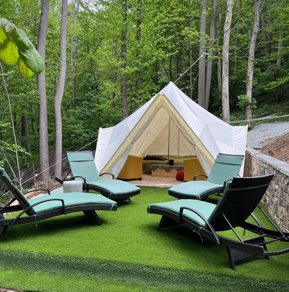 Bell tent in a forest setting with lounge chairs and outdoor furniture.