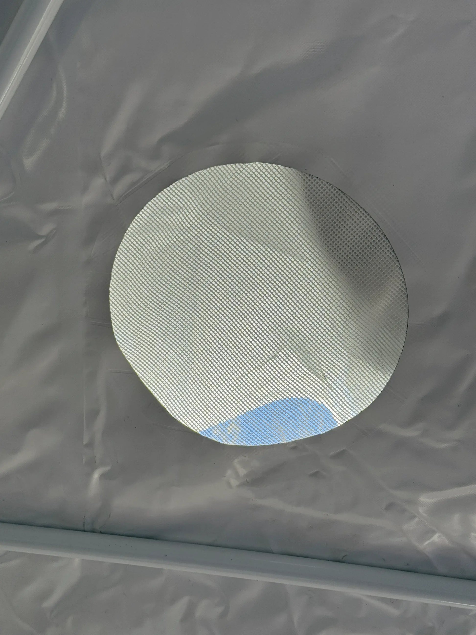 Circular window in a gray fabric wall with a textured white interior.